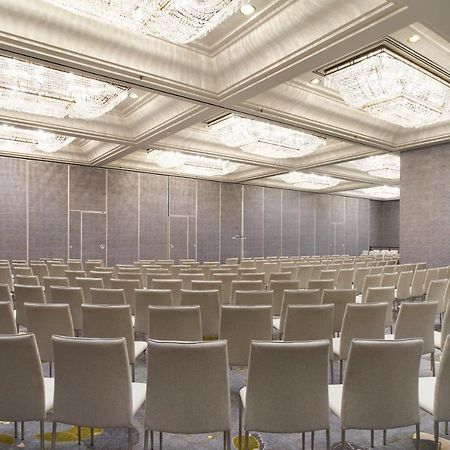 Hotel Park Lane New York Esterno foto The photo shows an empty conference room or event space. It features rows of light-colored chairs arranged in a neat pattern facing a front area. The room has a modern design, with elegant ceiling fixtures that include chandeliers, and the walls are 