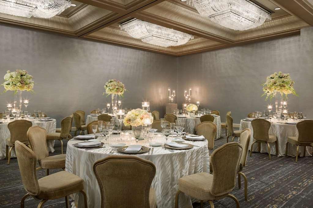 Hotel Park Lane New York Ristorante foto The photo shows an elegant dining room or banquet hall. There are several round tables covered with white tablecloths, each set with fine dining ware including plates, glasses, and utensils. The tables are adorned with floral arrangements in light co