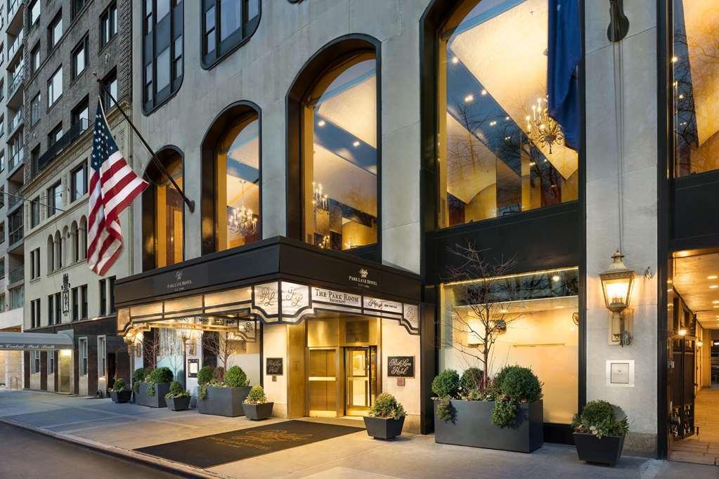 Hotel Park Lane New York Esterno foto The photo shows the exterior of a hotel, featuring a prominent entrance with large glass windows and a stylish facade. The building has a modern design with elegant architectural details and is accentuated by a series of large arches. A U.S. flag is 