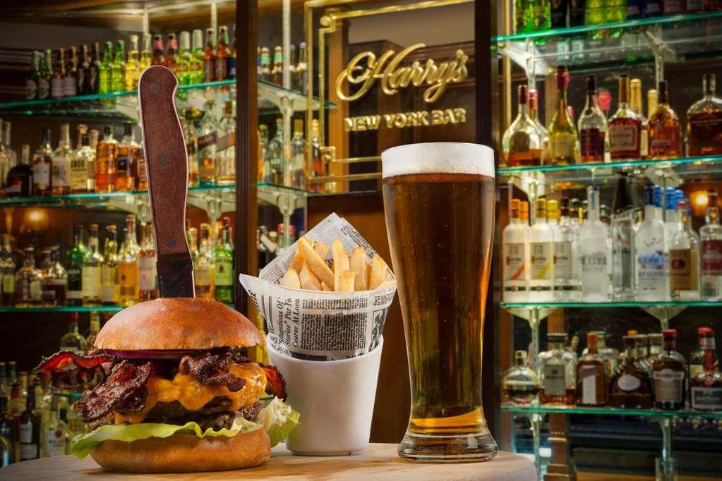 Hotel Park Lane New York Ristorante foto The photo features a delicious-looking burger placed prominently in the foreground, complete with toppings like lettuce and bacon. A knife is inserted into the top of the burger, adding a dramatic effect. Next to the burger, there is a small containe
