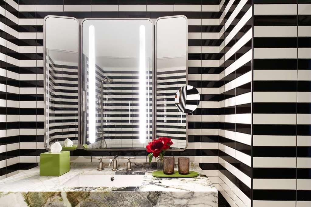 Hotel Park Lane New York Esterno foto The image shows a modern bathroom with a striking design. The walls are decorated with bold black and white stripes, creating a dramatic visual effect. There are large mirrors above the sink, framed in a sleek metallic finish, and bright, vertical LE
