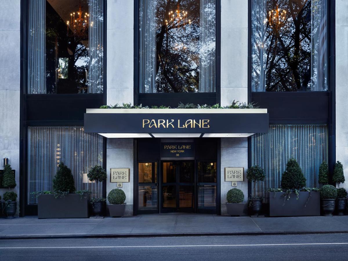 Hotel Park Lane New York Esterno foto The photo shows the entrance of a hotel or building named "Park Lane." The façade features large glass windows, elegant lighting fixtures, and decorative elements like potted plants. The entrance is framed by a dark awning with the name "PARK LANE" p