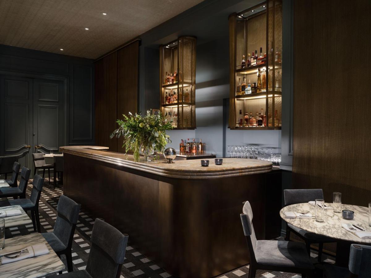 Hotel Park Lane New York Esterno foto The photo shows a stylish and elegant bar area. The bar is made of a smooth, light-colored stone, and it is complemented by dark wooden panels and shelves. Behind the bar, there are illuminated shelves displaying various bottles of liquor, enhancing 