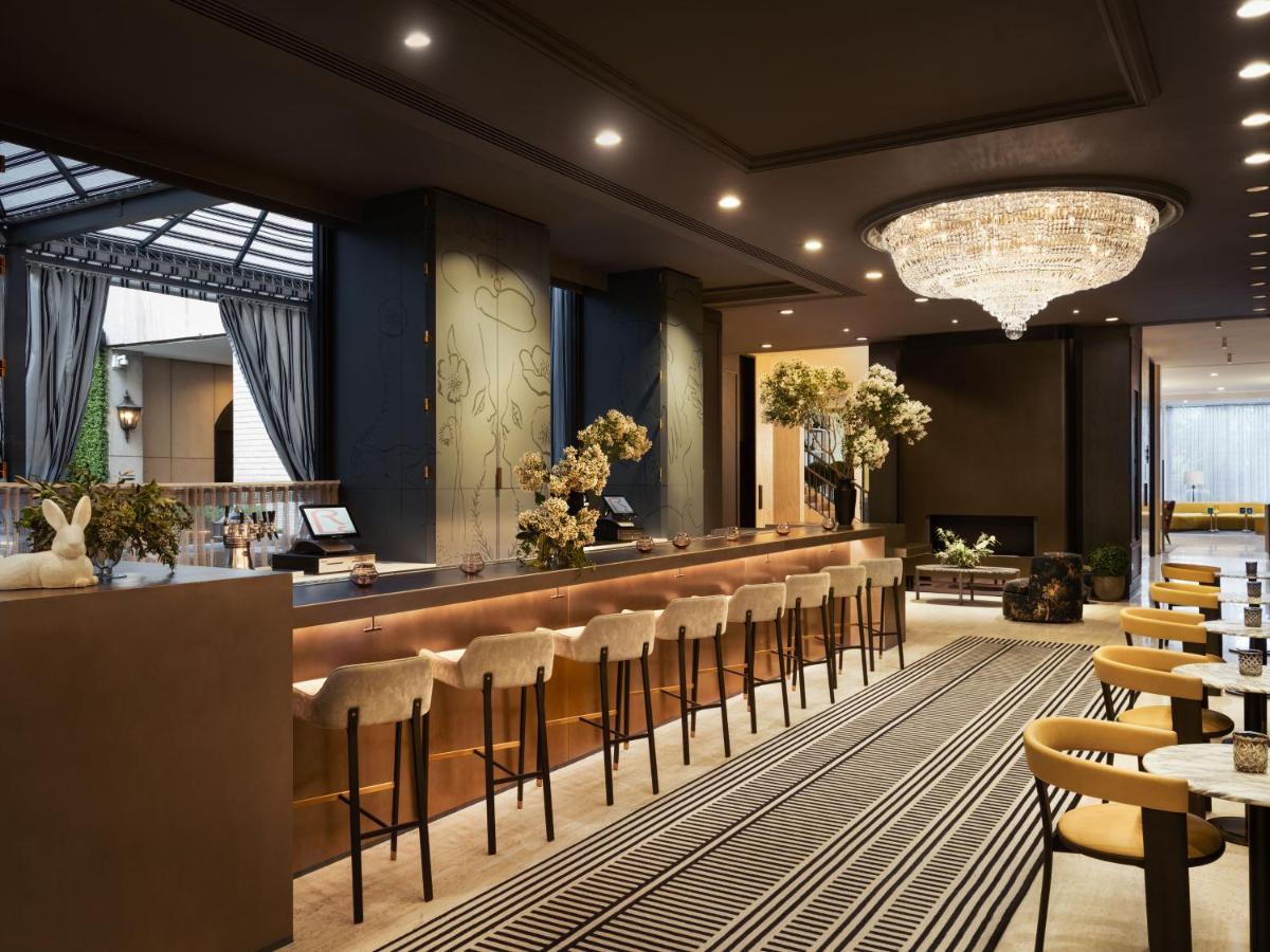 Hotel Park Lane New York Esterno foto The photo shows the interior of a stylish hotel lobby. There is a long reception bar with high stools, where guests likely check in or receive assistance. The decor features elegant lighting, including a large chandelier hanging from the ceiling. The