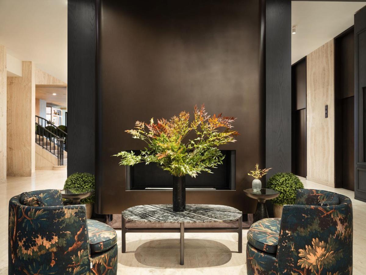 Hotel Park Lane New York Esterno foto The photo depicts a stylish interior space, likely a lobby or lounge area. In the center, there is a table adorned with a large floral arrangement featuring vibrant foliage. Surrounding the table are two upholstered chairs with a floral pattern that 