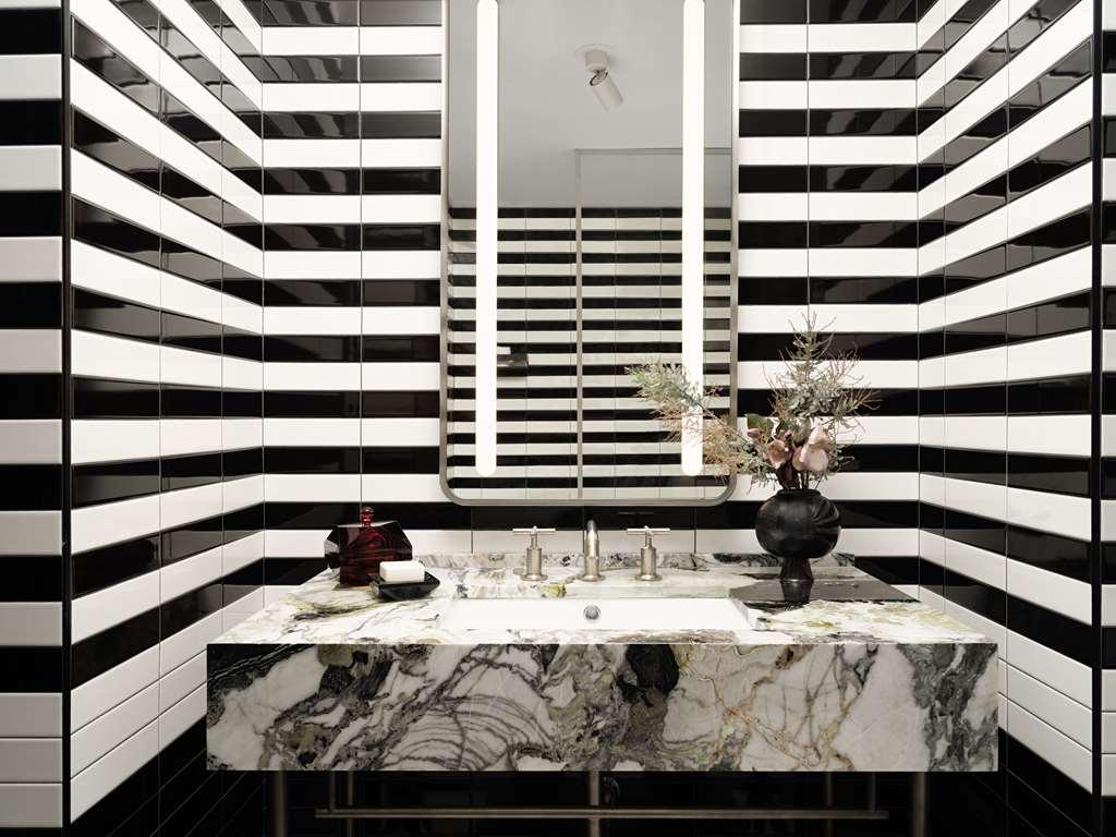Hotel Park Lane New York Camera foto The photo shows a modern bathroom with a striking design. The walls are decorated with alternating black and white stripes, creating a bold visual effect. In the center, there is a large, stylish vanity featuring a marble countertop with intricate pa