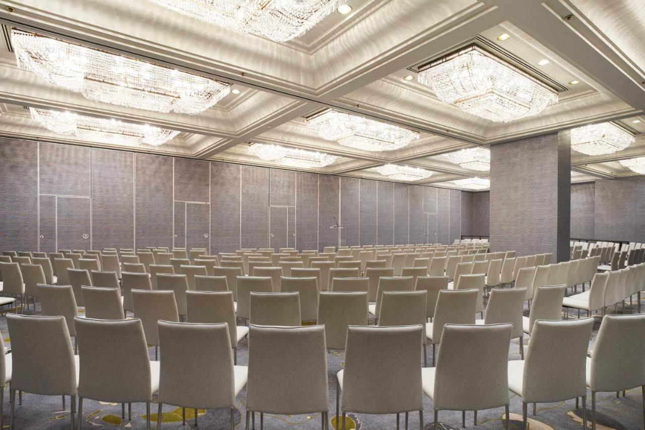 Hotel Park Lane New York Esterno foto The photo shows an empty conference room or event space. It features rows of light-colored chairs arranged in a neat pattern facing a front area. The room has a modern design, with elegant ceiling fixtures that include chandeliers, and the walls are 