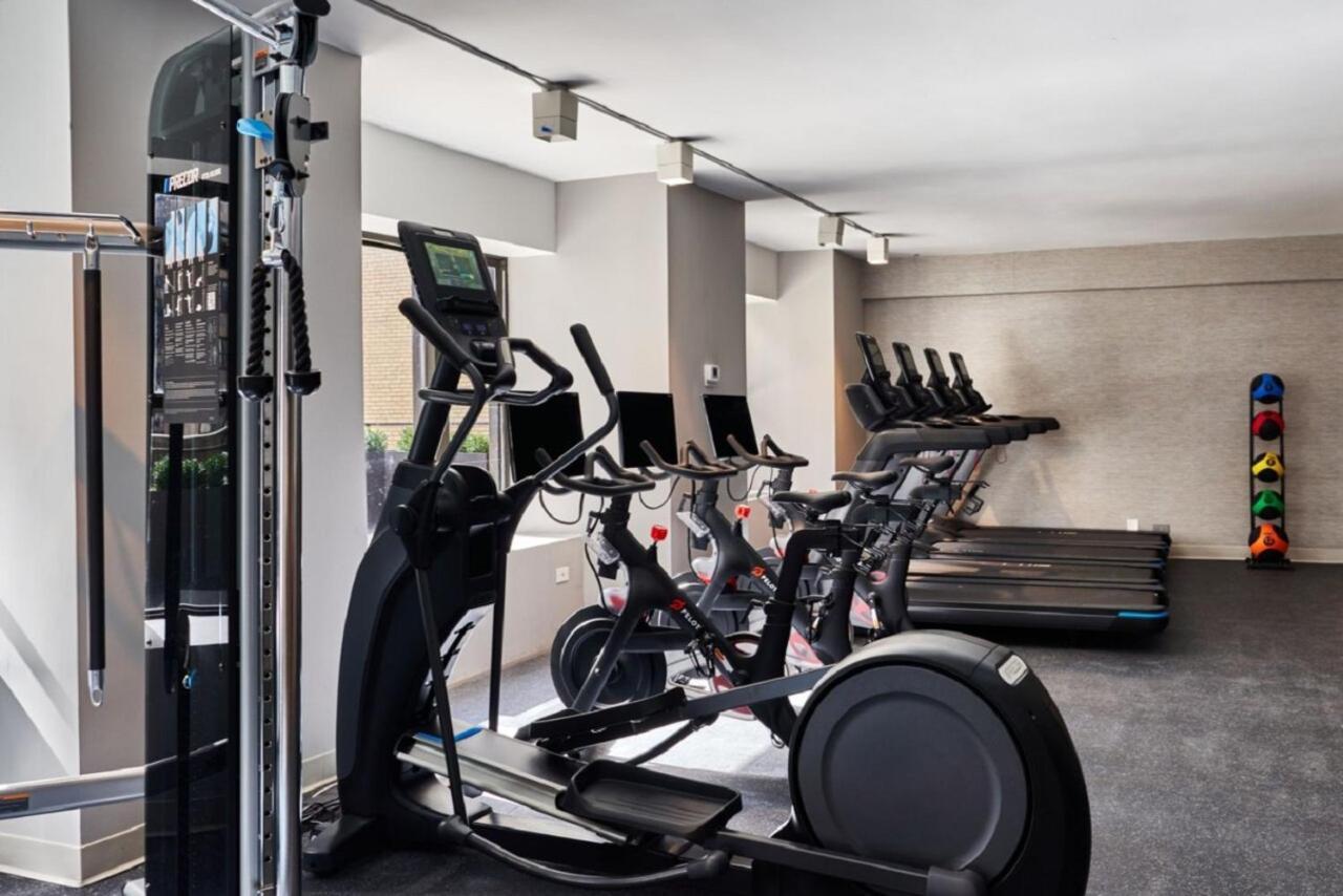 Hotel Park Lane New York Esterno foto The photo shows a gym interior equipped with various fitness machines. On the left, there is a multi-functional weight machine, and next to it, there are several elliptical machines with digital displays. In the background, there are stationary bikes