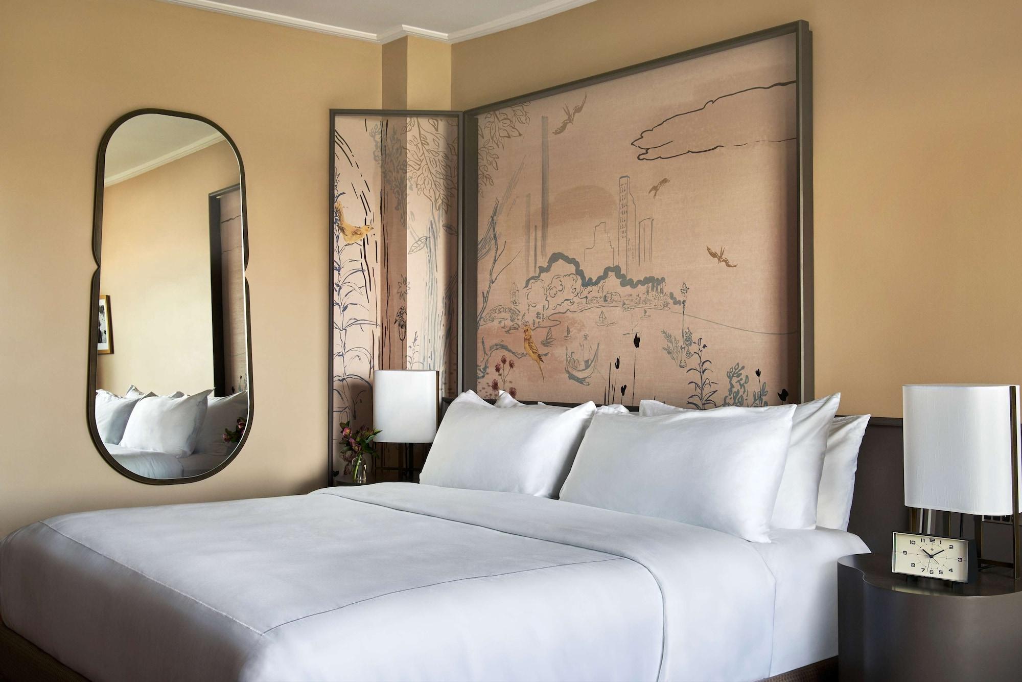 Hotel Park Lane New York Esterno foto The photo shows a modern bedroom with a light, neutral color scheme. There is a large bed with crisp white linens and multiple pillows. Behind the bed is an artistic feature that includes a painted wall mural, likely depicting nature or a serene land