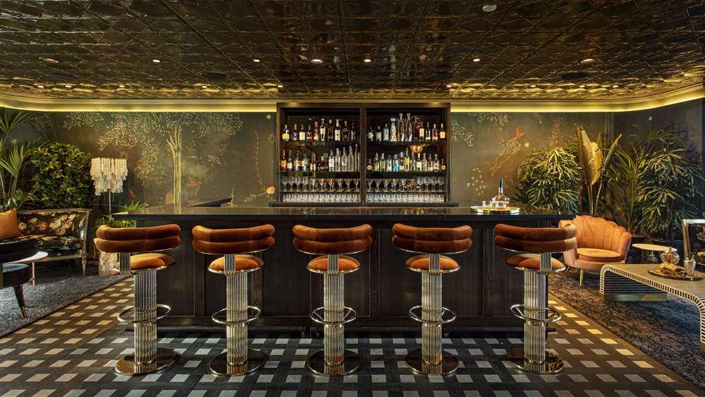Hotel Park Lane New York Ristorante foto The photo showcases an elegant bar area. It features a long bar countertop with five stylish high stools, each with a plush brown cushion. Behind the bar, there is a cabinet filled with an assortment of bottles and glassware, indicating a well-stocke
