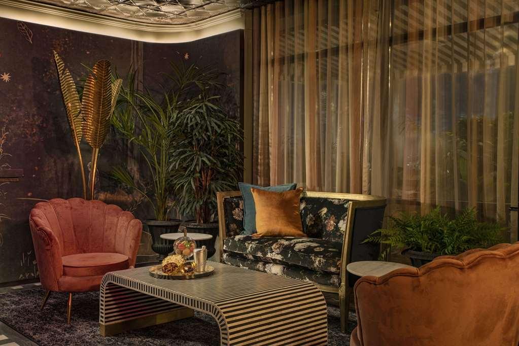 Hotel Park Lane New York Ristorante foto The photo depicts a stylish and elegantly arranged indoor seating area. There are two distinctive chairs, one pink velvet armchair and another in a light peach hue, both featuring curved designs. In the center is a unique coffee table with a striped 