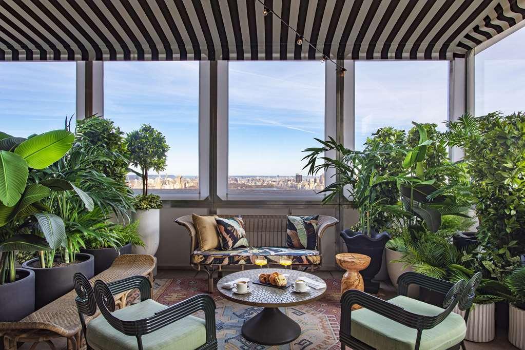 Hotel Park Lane New York Ristorante foto The photo shows a beautifully designed indoor space that resembles a cozy sitting area. It features large windows with a view of the outdoors, allowing natural light to enter. The area is adorned with lush green plants, creating a refreshing and vibr