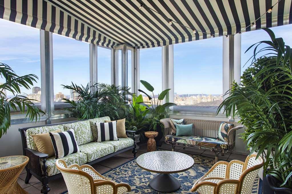 Hotel Park Lane New York Ristorante foto The photo showcases a beautifully decorated sunroom or conservatory. It features a comfortable seating area with a green and white patterned sofa adorned with black and white striped cushions. There's a round table in the center with a decorative sur