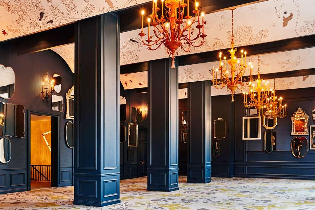 Hotel Park Lane New York Servizi foto The photo depicts an elegant interior space featuring high ceilings and large, dark columns. The walls are predominantly a deep shade, possibly navy or black, which creates a dramatic atmosphere. Ornate chandeliers hang from the ceiling, adding a tou