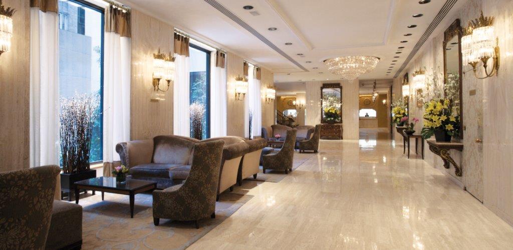 Hotel Park Lane New York Esterno foto The photo shows an elegant hotel lobby with a spacious and well-lit layout. The floors are marble, giving a polished appearance. On one side, there are several comfortable seating areas, including chairs and sofas arranged around small tables. Large 