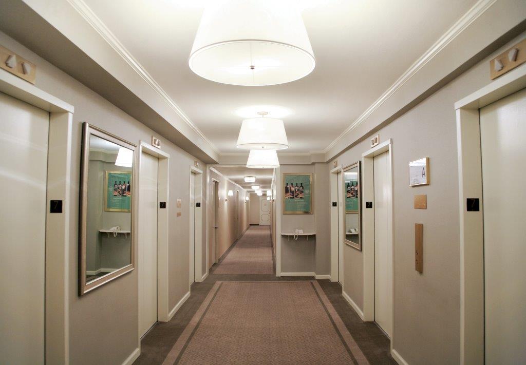 Hotel Park Lane New York Esterno foto The photo shows a well-lit hotel corridor. On either side, there are doors with small black numbers indicating room numbers. Each door has a mirror beside it. The walls are painted a soft neutral color, and the ceiling features overhead lights, creat