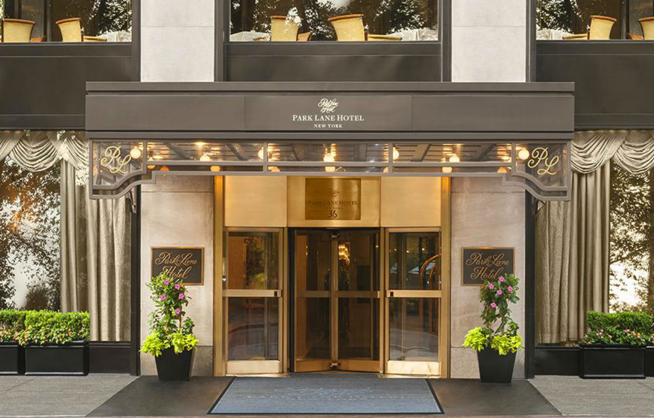 Hotel Park Lane New York Esterno foto The photo shows the entrance of a hotel named the Park Lane Hotel. It features a glass revolving door framed by elegant awning and decorative elements. Flanking the entrance are planters with greenery, and the hotel’s name is displayed prominently ab